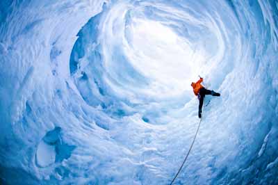 Iceland, man climbing wall of ice cave, low angle view